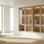 Bright, airy modern living room with a recessed light wood display cabinet, LED-lit shelves, minimalist decor, gray sofa, and large windows.