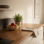 Cuisine moderne avec comptoir en bois, fruits et plante. Des silhouettes de rat, cafard et punaise de lit sont subtilement intégrées.