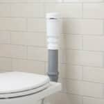 Clapet aérateur blanc sur tuyau gris près d'un WC blanc et un mur carrelé clair.