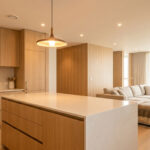 Cuisine moderne en bois avec îlot central en pierre ouvrant sur un salon chaleureux et lumineux.