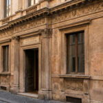 Façade d'un bâtiment historique en pierre à Rome, illustrant des détails architecturaux complexes et classiques.